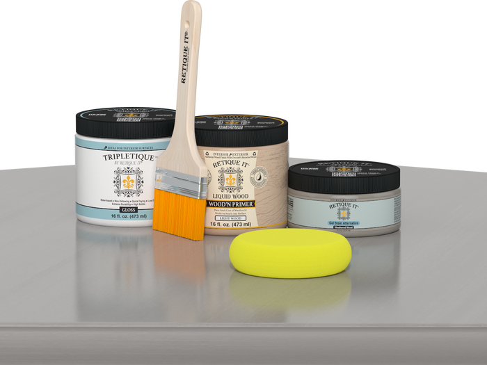 Retique It® Weathered Wood Multipurpose Kit contents with Liquid Wood primer, Weathered Wood gel stain alternative, Tripletique gloss interior top coat, paintbrush, and yellow sponge displayed on a gray wood surface.