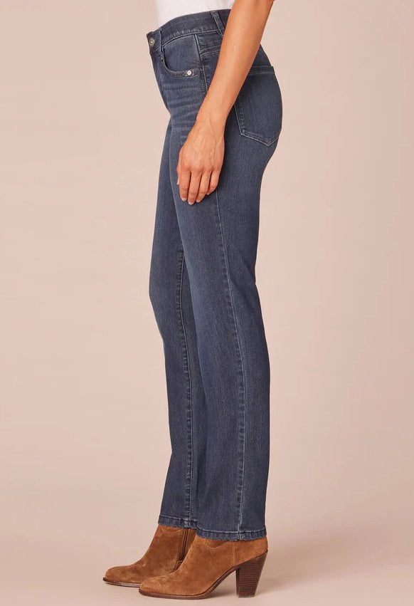 Person wearing blue jeans and brown boots on a beige background