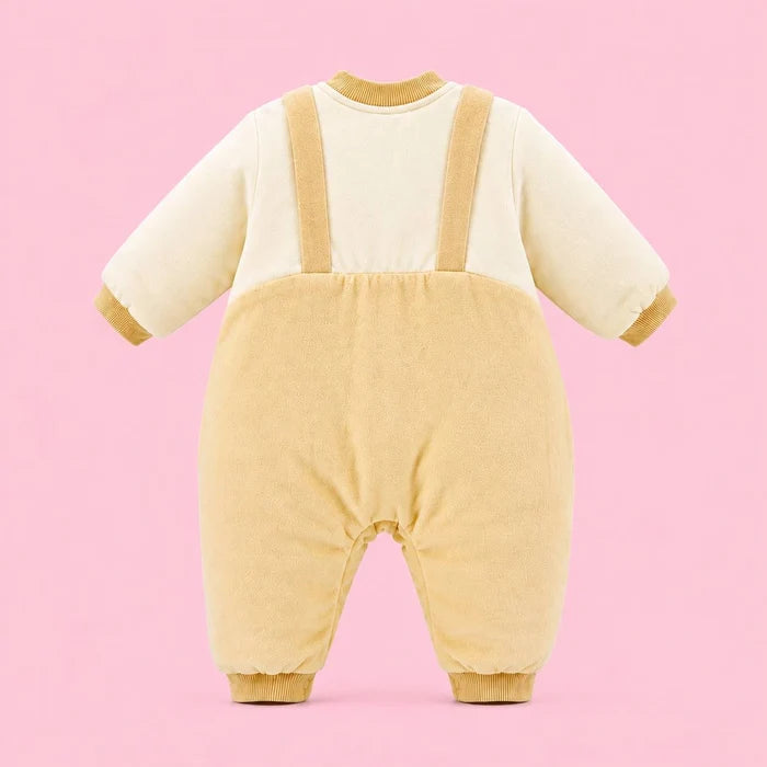 A baby snowsuit or one-piece outfit shown from the back, featuring a mustard cream-colored upper body and sleeves with tan suspenders and cuffs, and a tan corduroy-like lower body, set against a solid pink background.