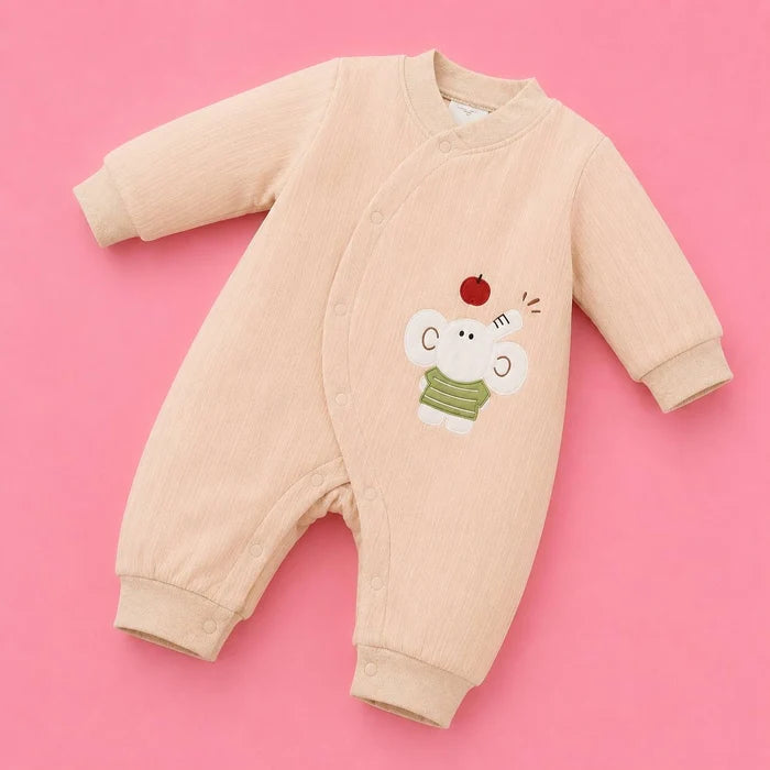 A long-sleeve baby romper in a light beige corduroy fabric, featuring a cute embroidered elephant character wearing a green striped shirt with a small red apple on its head, set against a solid pink background.