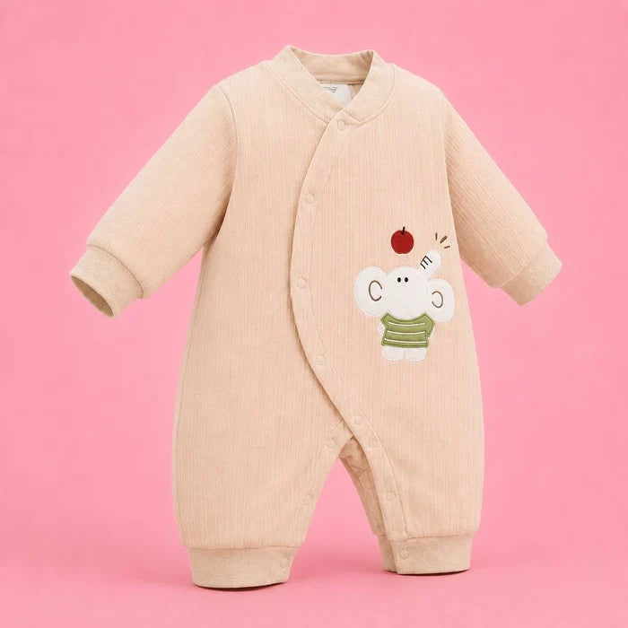 A baby long-sleeve footless sleeper in a light beige ribbed fabric, featuring a cute cartoon elephant wearing a green striped shirt and a red apple on the chest, set against a solid pink background.