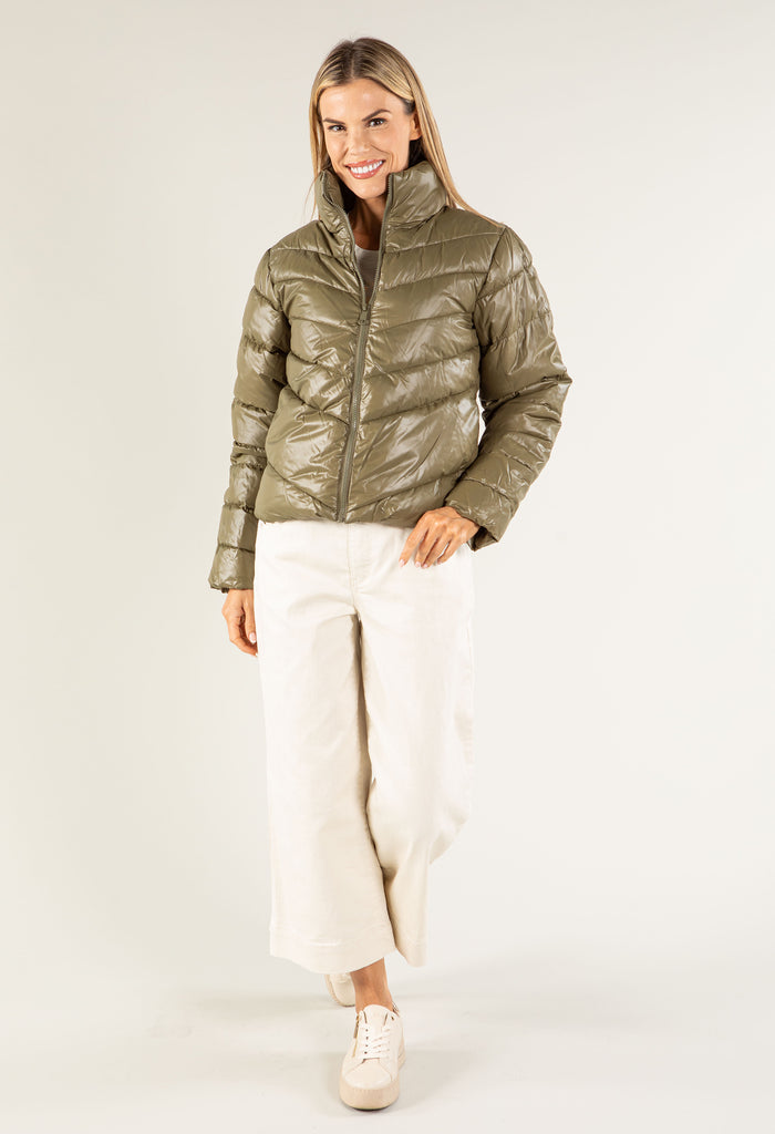 Woman wearing a green puffer jacket on a white background
