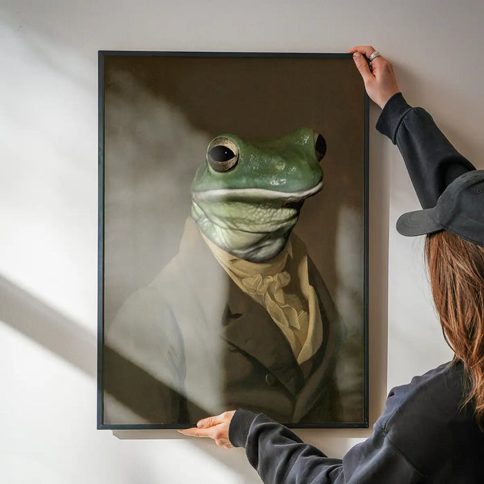 Frog Head Portrait Print being hung on a wall in a black frame