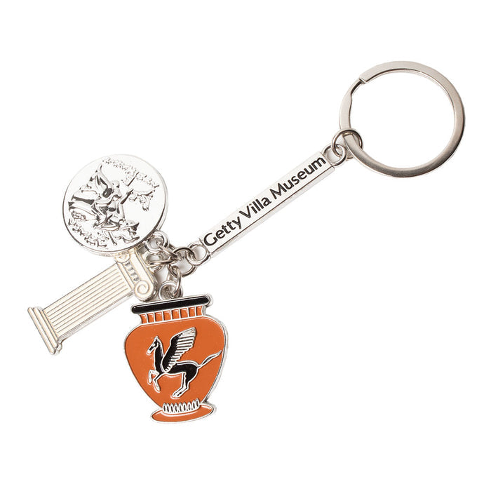 A keychain with three metal and enamel charms, including a Pegasus vase, a Ancient Greek coin, and an Ionic column, with the Getty Villa Museum branding.