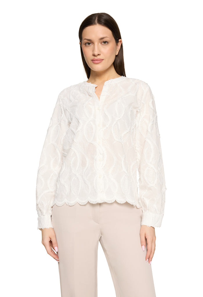 Woman wearing a white lace blouse and beige pants on a white background