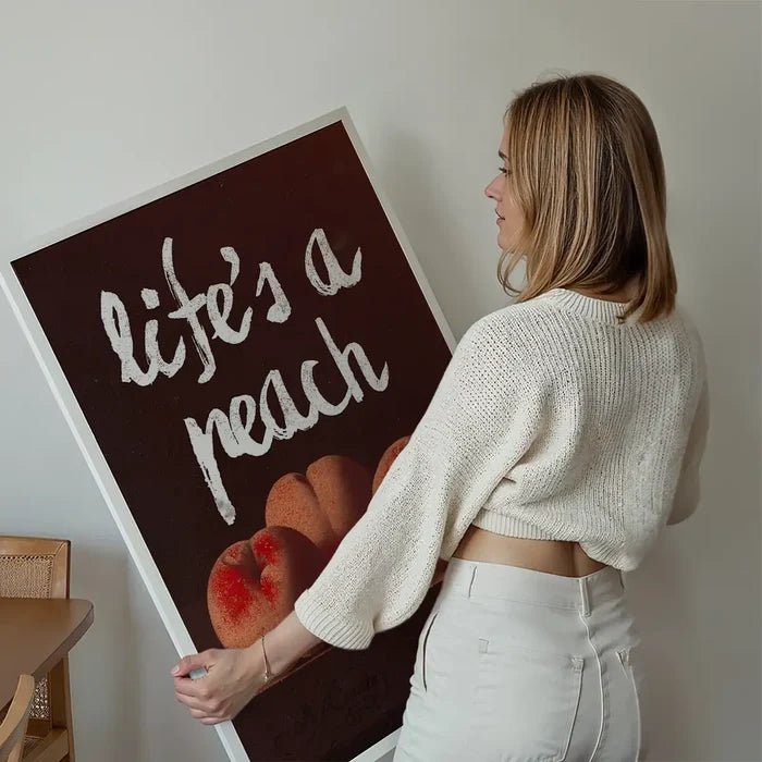 Life's A Peach Altered Art Print held up against a living room wall