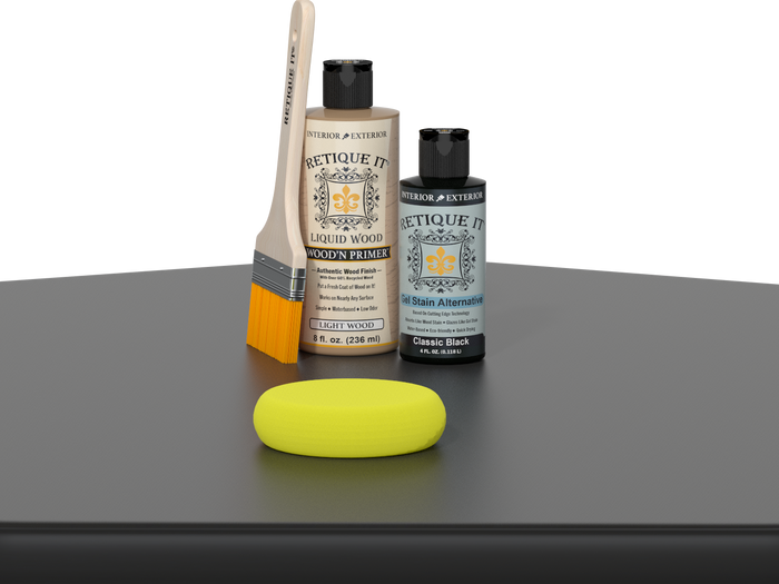 Retique It® Classic Black Kit with Light Wood’n Primer, Classic Black Gel Stain Alternative, paintbrush, and yellow sponge on a black tabletop.