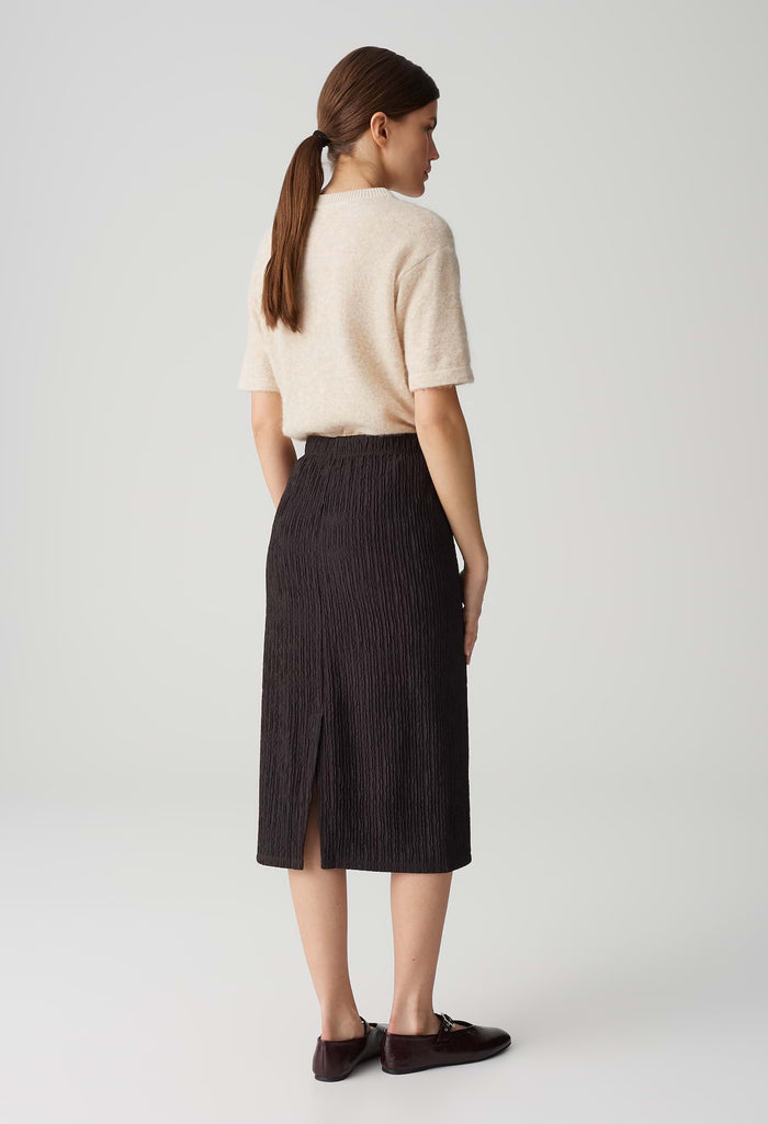 Woman wearing a beige sweater and black pinstripe skirt on a white background