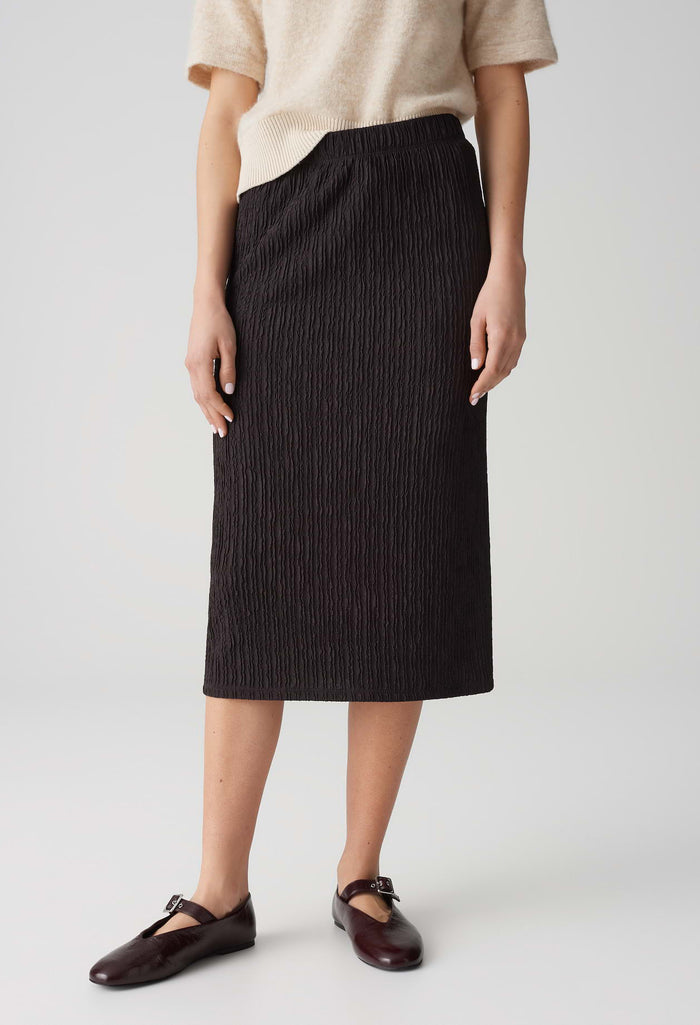 Person wearing a black skirt with a plain background