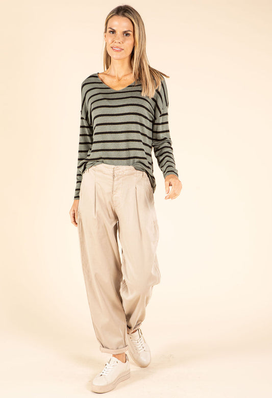 Woman wearing a striped sweater and beige pants on a beige background