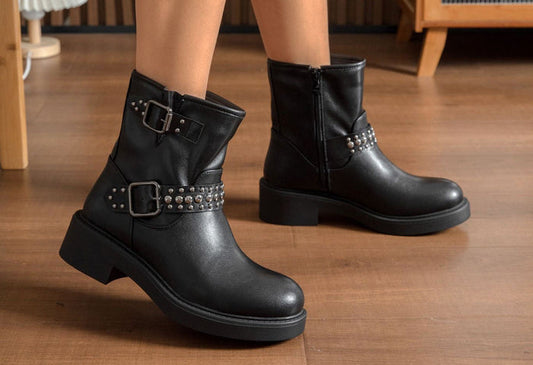 Black leather boots with buckles on a wooden floor