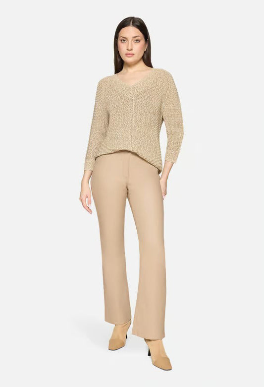 Woman wearing a beige sweater and pants on a white background