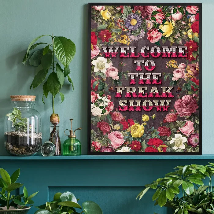 Welcome to the Freakshow Typography Maximalist Print, floral art print black framed on a living room shelf